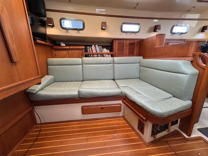 Slide: The Image of Interior of 1999 Island Packet 45 yacht with green leather seating and wooden flooring. - 31