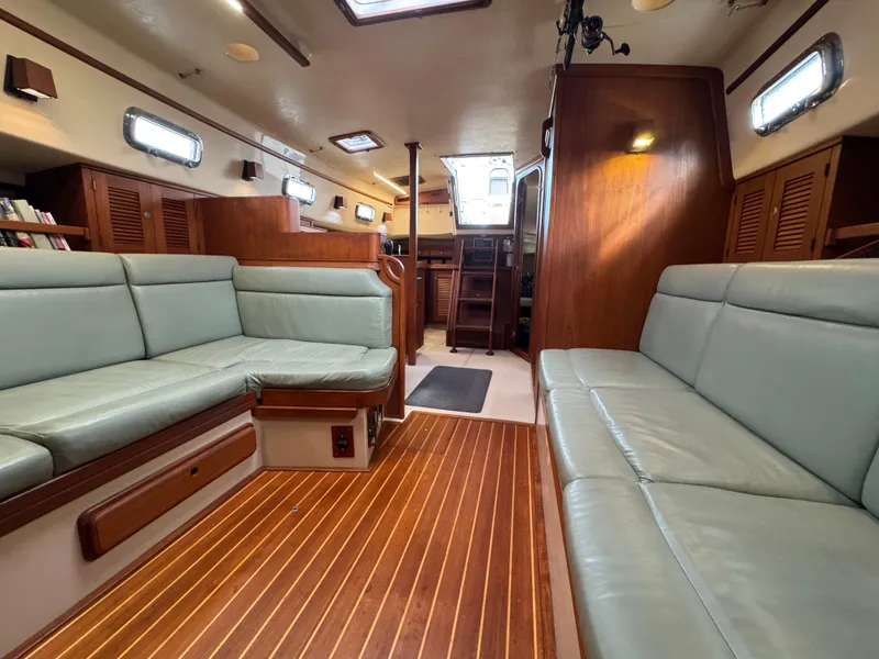 Slide: The Image of Interior of 1999 Island Packet 45 sailboat with wood flooring and cushioned seating. - 34