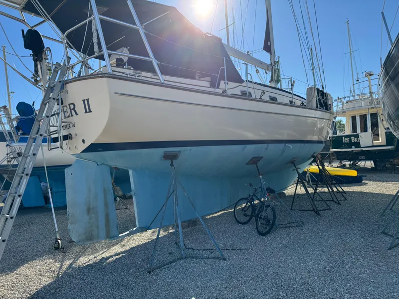 Slide: The Image of Island Packet 45 sailboat from 1999 on stands in a boatyard, with a bicycle nearby. - 4