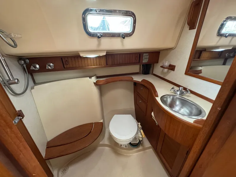 Slide: The Image of 1999 Island Packet 45 yacht bathroom with wooden accents, sink, and toilet. - 44