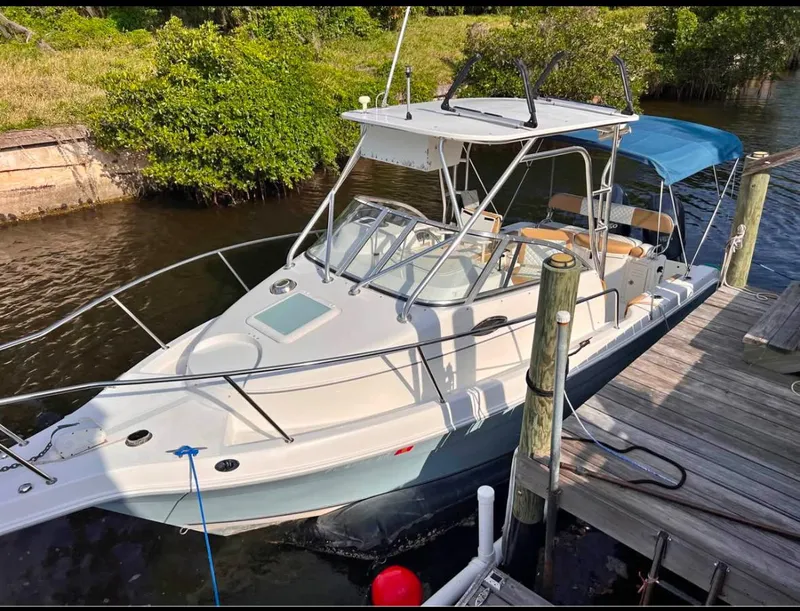 The Image of 2004 Cobia 250 Walk-Around boat docked by a wooden pier. - 1