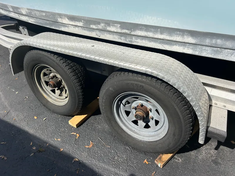 Slide: The Image of Trailer wheels of a 2004 Cobia 250 Walk-Around boat on a paved surface. - 16