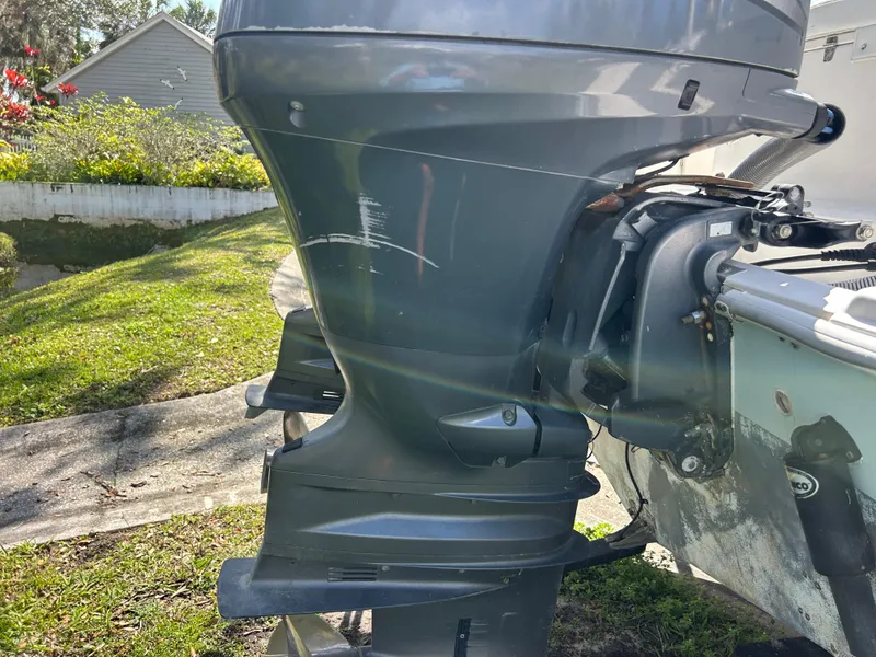 Slide: The Image of 2004 Cobia 250 Walk-Around boat motor with visible scratches, parked on grass. - 18