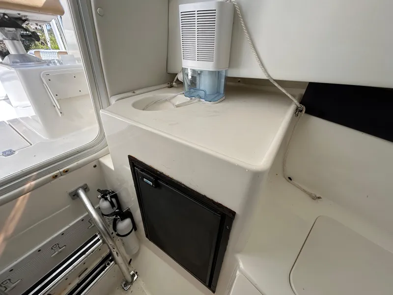 Slide: The Image of 2004 Cobia 250 Walk-Around boat interior with sink and storage compartment. - 23