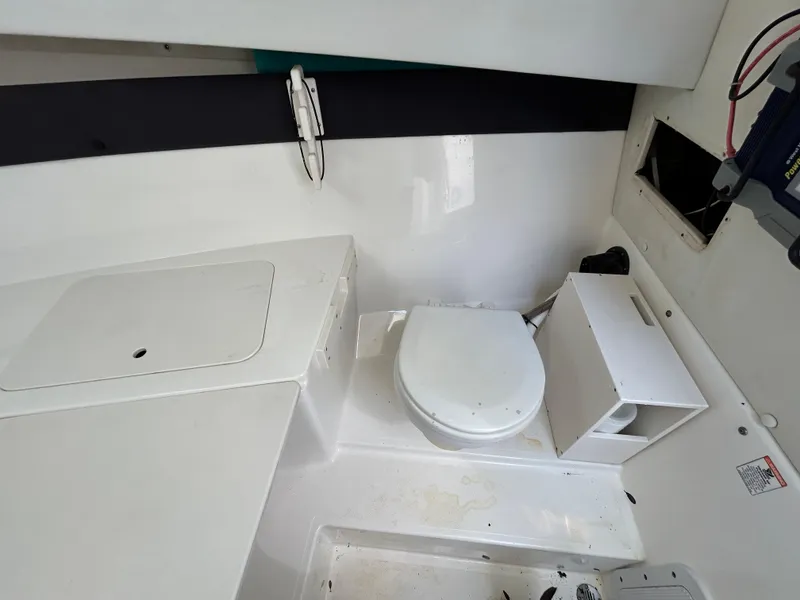 Slide: The Image of 2004 Cobia 250 Walk-Around boat interior with toilet and storage compartments. - 25