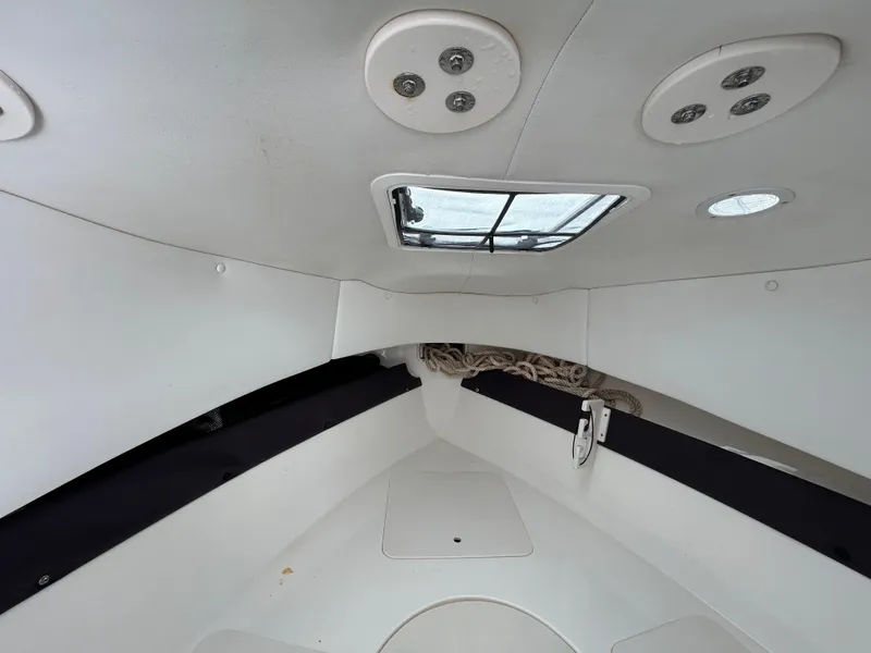 Slide: The Image of Interior cabin view of 2004 Cobia 250 Walk-Around boat, featuring ceiling lights and a hatch. - 27