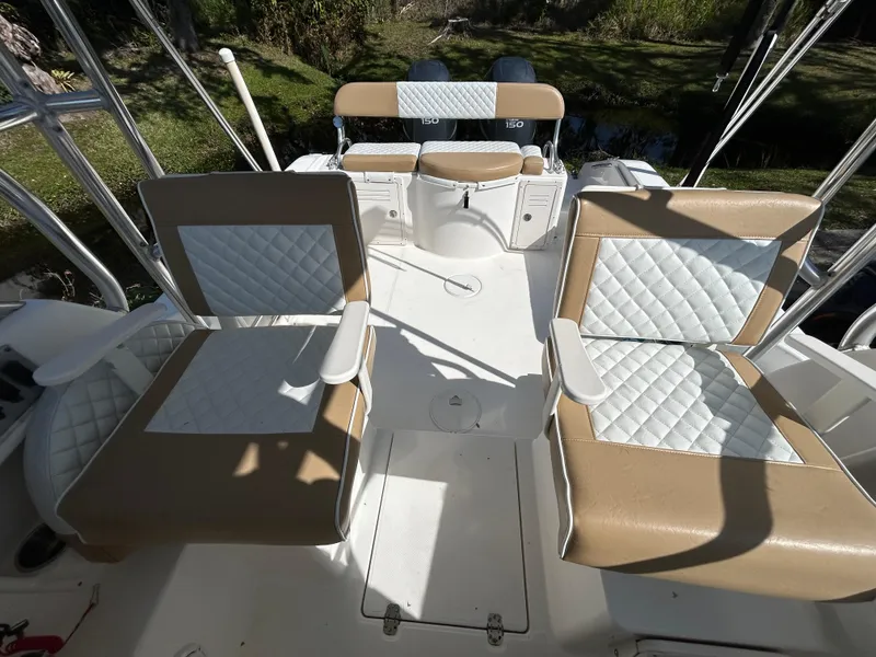 Slide: The Image of 2004 Cobia 250 Walk-Around boat interior with cushioned seating and fishing rod holders. - 28