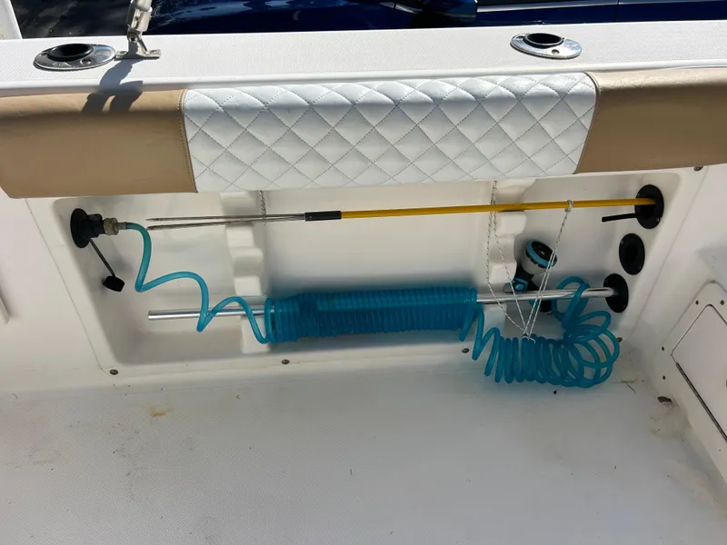 Slide: The Image of 2004 Cobia 250 Walk-Around boat storage with fishing rod and coiled hose. - 29