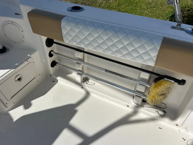 Slide: The Image of 2004 Cobia 250 Walk-Around boat interior with rod holders and cushioned backrest. - 30