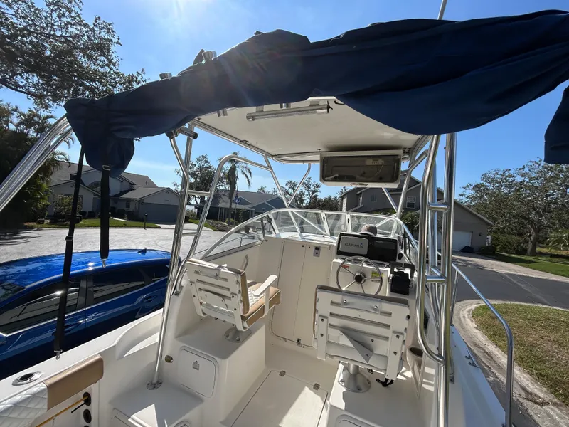 Slide: The Image of 2004 Cobia 250 Walk-Around boat interior with seating and canopy, parked in residential area. - 31