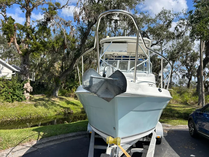Slide: The Image of 2004 Cobia 250 Walk-Around boat on trailer, surrounded by trees and blue sky. - 5