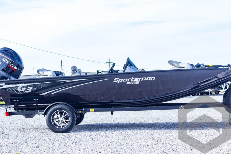 Slide: The Image of 2025 G3 Sportsman 1710 boat on trailer, sleek black design, parked on gravel. - 14