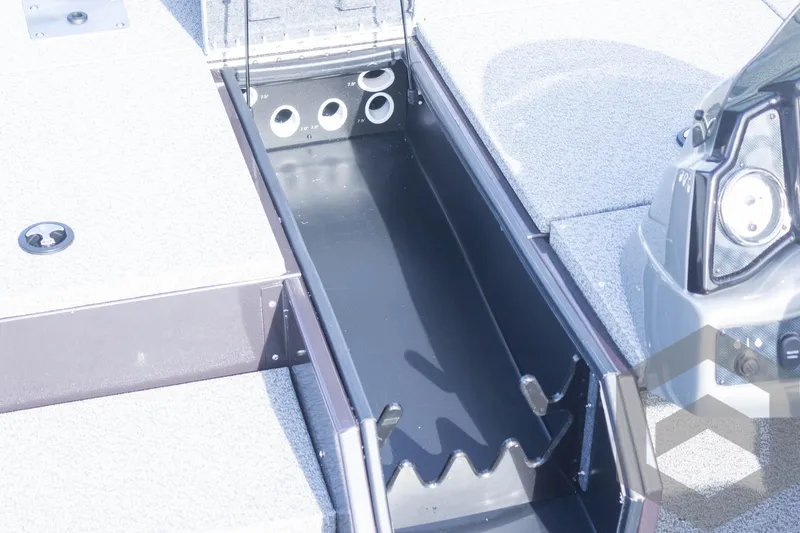 Slide: The Image of 2025 G3 Sportsman 1710 boat storage compartment with rod holders and carpeted deck. - 23