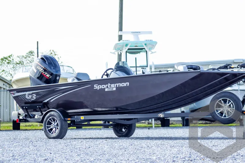 Slide: The Image of 2025 G3 Sportsman 1710 boat on trailer, sleek black design, parked outdoors. - 9