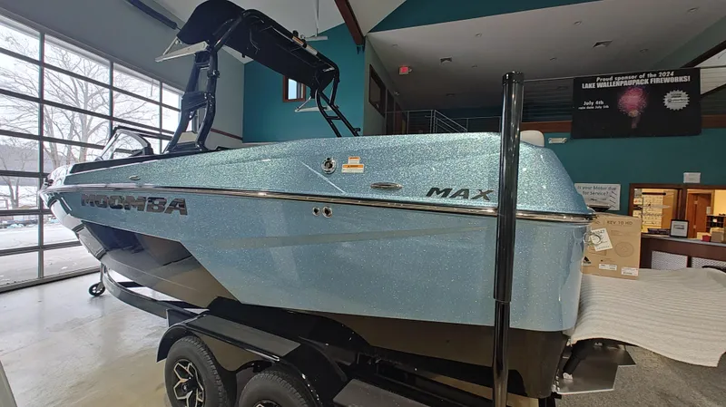 Slide: The Image of 2025 Moomba Max boat in showroom, metallic blue finish, on trailer. - 11