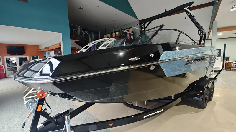 Slide: The Image of 2025 Moomba Max boat in showroom, sleek black design on trailer. - 12