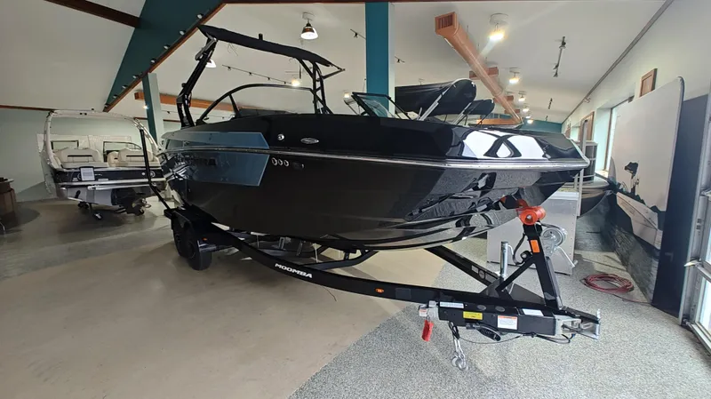 Slide: The Image of 2025 Moomba Max boat in showroom, sleek black design on trailer. - 13