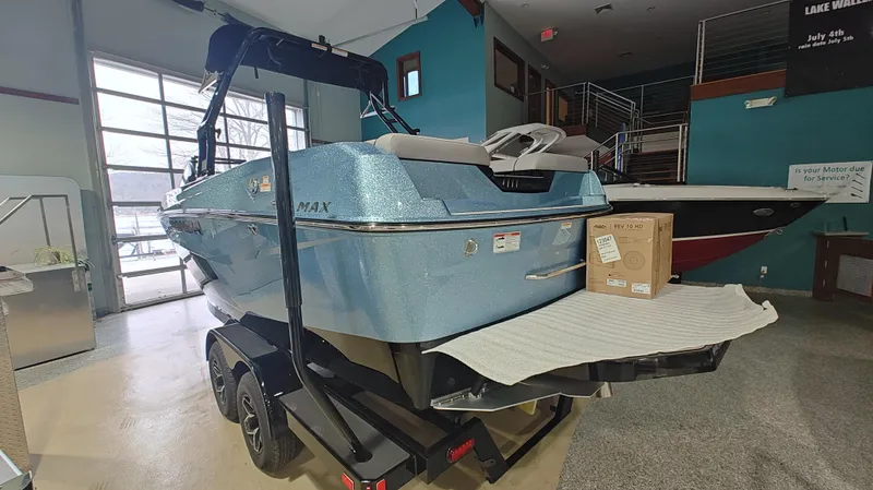 Slide: The Image of 2025 Moomba Max boat in showroom, blue exterior, on trailer. - 2
