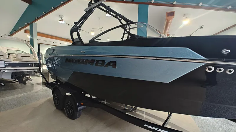 Slide: The Image of 2025 Moomba Max boat in showroom, sleek design, black and blue exterior. - 4