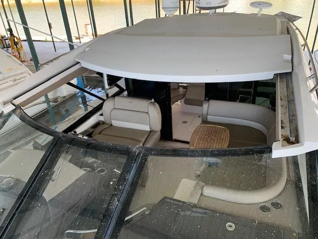 Slide: The Image of 2014 Regal 44 Sport Coupe interior with seating and table, docked in a marina. - 22