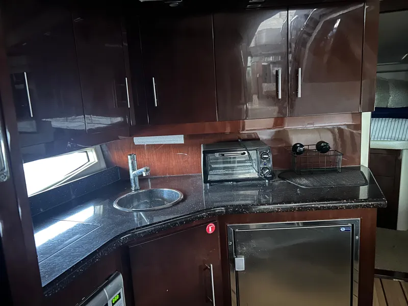 Slide: The Image of Luxurious 2014 Regal 44 Sport Coupe yacht kitchen with dark wood cabinets and modern appliances. - 7