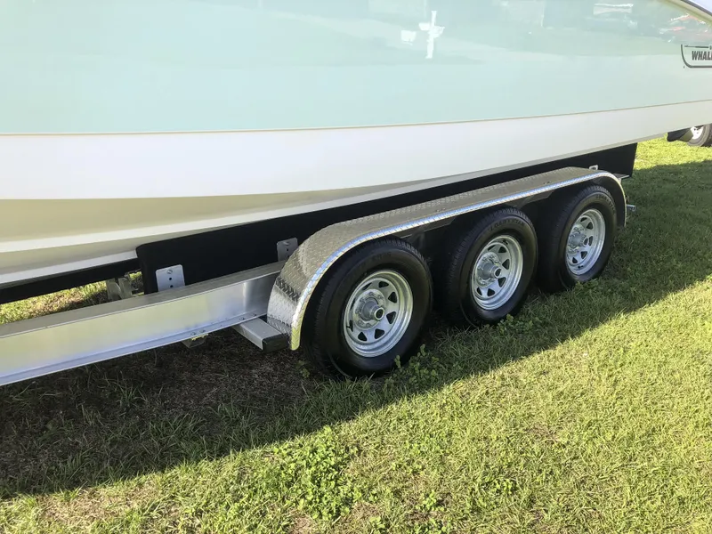 Slide: The Image of 2004 Boston Whaler 32 Outrage on a triple-axle trailer, parked on grass. - 14