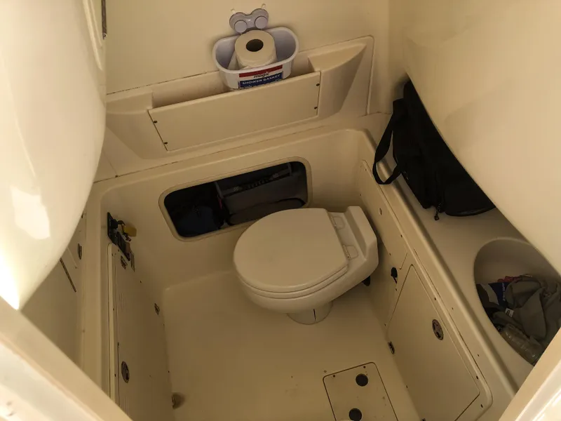 Slide: The Image of 2004 Boston Whaler 32 Outrage boat bathroom interior with toilet and storage. - 24