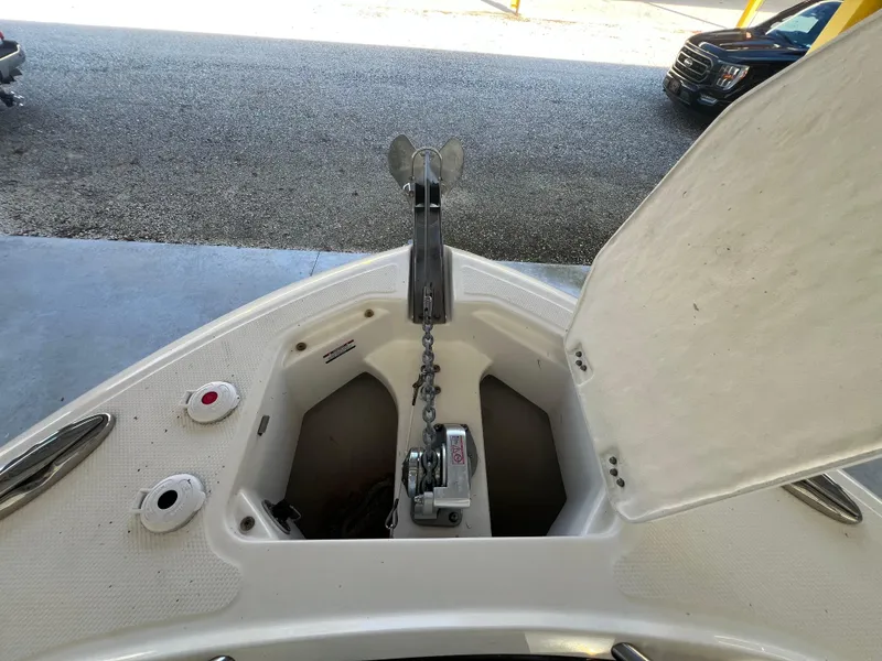 Slide: The Image of 2019 Robalo R242 Explorer anchor compartment with open hatch, showcasing anchor chain and winch. - 24
