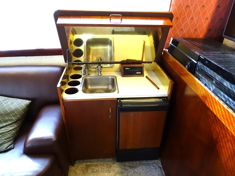 Slide: The Image of 1987 Ocean Yachts 48 interior kitchenette with sink, mini-fridge, and wood cabinetry. - 15