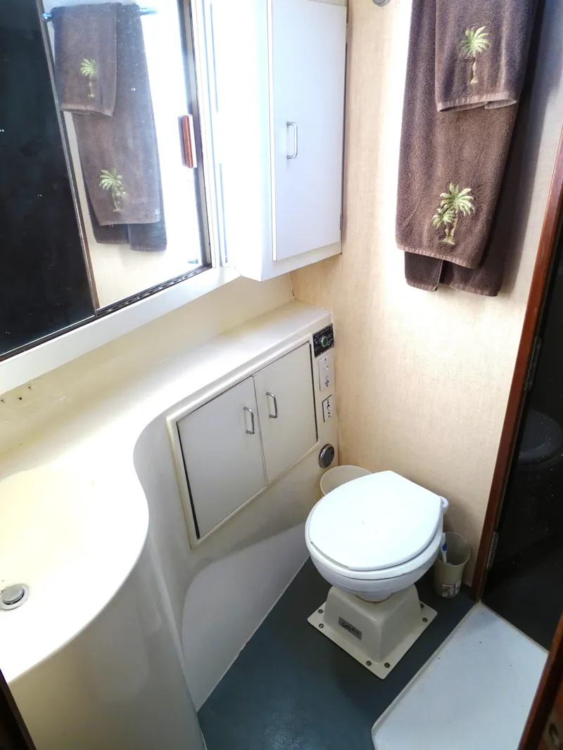 Slide: The Image of 1987 Ocean Yachts 48 bathroom with compact design, white fixtures, and palm tree towels. - 25