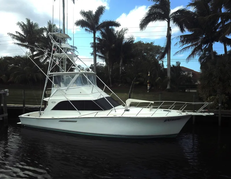 Slide: The Image of 1987 Ocean Yachts 48 boat docked near palm trees under a partly cloudy sky. - 36