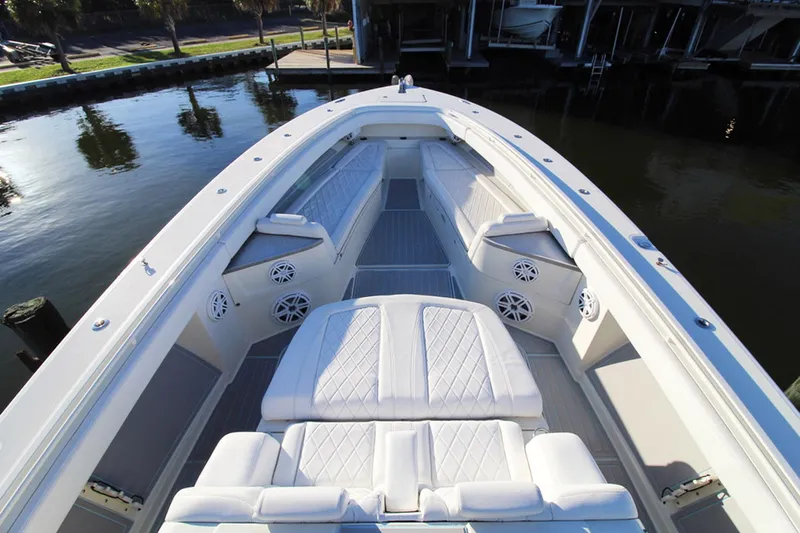 Slide: The Image of 2017 HCB Suenos boat interior with white seating and speakers, docked by calm water. - 25