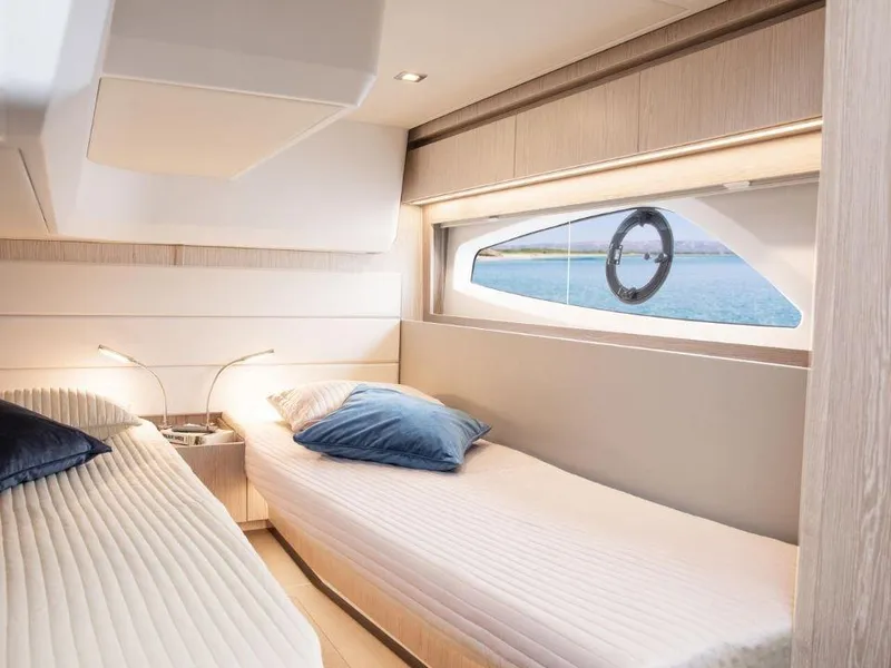 Slide: The Image of 2025 Sealine C390 yacht interior with twin beds and ocean view window. - 20