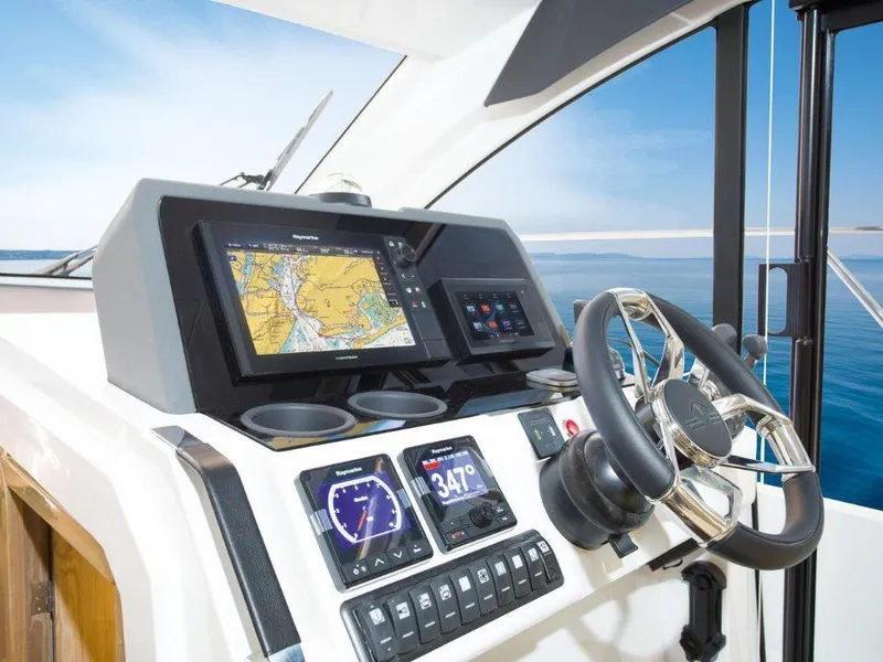 Slide: The Image of 2025 Sealine C390 yacht helm with navigation screens and steering wheel, overlooking the ocean. - 7