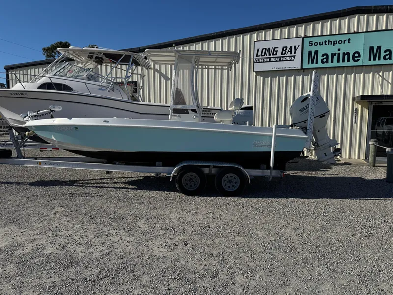 Slide: The Image of 2020 Long Bay 230 Bay boat on trailer with Suzuki outboard motor, American flag, clear sky. - 0
