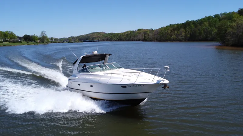 The Image of 2004 Cruisers Yachts 370 Express speeding on a scenic lake. - 0