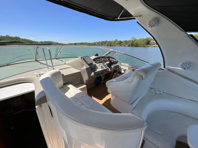 Slide: The Image of 2004 Cruisers Yachts 370 Express cockpit with white seating, overlooking serene lake view. - 16