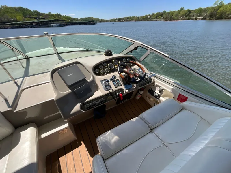 Slide: The Image of 2004 Cruisers Yachts 370 Express helm with leather seating, overlooking serene lake view. - 19