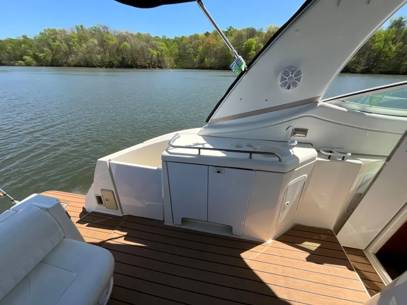 Slide: The Image of 2004 Cruisers Yachts 370 Express boat deck with seating, overlooking serene lake and lush trees. - 20