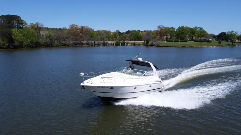 Slide: The Image of 2004 Cruisers Yachts 370 Express speeding on a serene lake under clear blue skies. - 6
