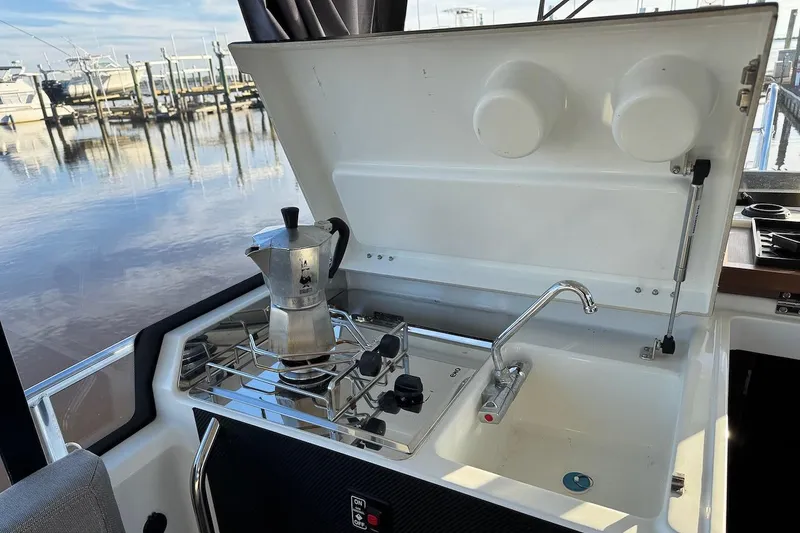 Slide: The Image of Jeanneau NC Sport 895 2020 boat kitchen with stove and sink by the water. - 13