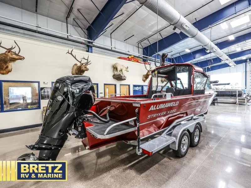 Slide: The Image of Red 2025 Stryker X220 boat on trailer in showroom with mounted animal heads. - 4