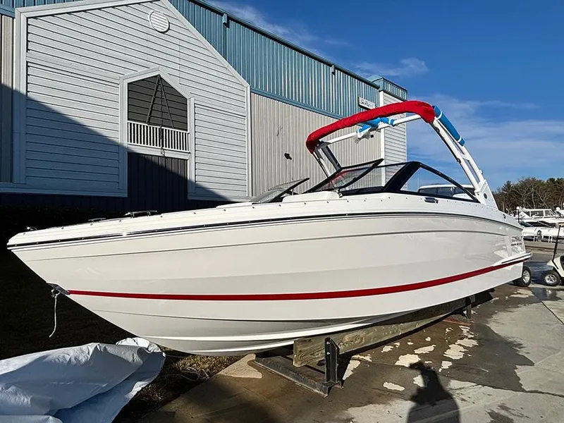 The Image of 2025 Cobalt R4 Outboard boat with red accents, docked near a building under clear blue sky. - 0
