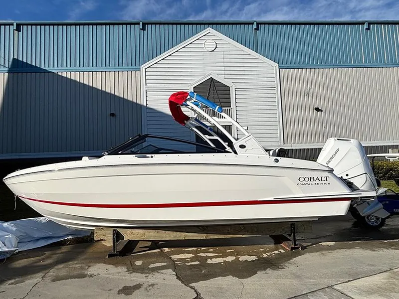 Slide: The Image of 2025 Cobalt R4 Outboard boat, white with red accents, parked outdoors near a building. - 3