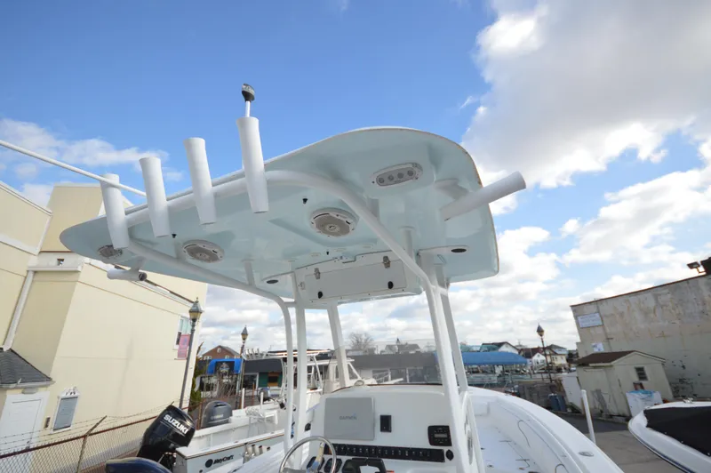 Slide: The Image of 2015 Sea Hunt Gamefish 27 boat with T-top and rod holders under a blue sky. - 18