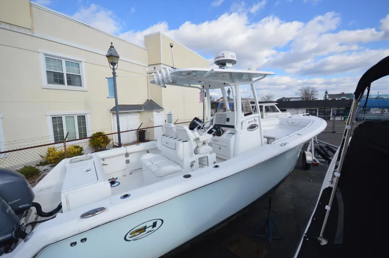 Slide: The Image of 2015 Sea Hunt Gamefish 27 boat docked outdoors under a cloudy sky. - 2