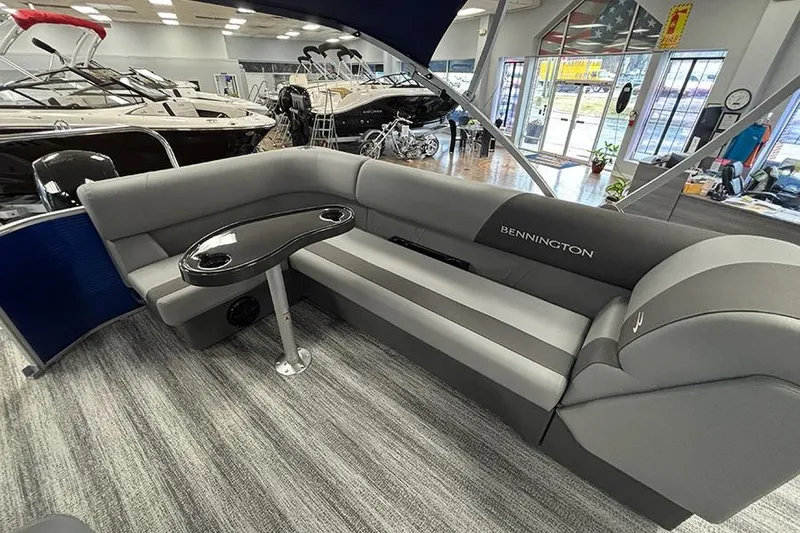 Slide: The Image of 2025 Bennington S 21 Cruise boat interior with gray seating and table in showroom. - 11