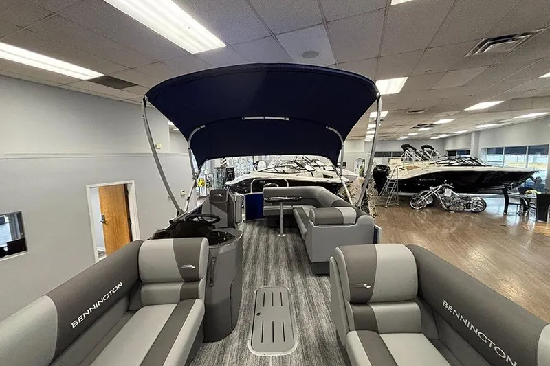 Slide: The Image of 2025 Bennington S 21 Cruise pontoon boat interior in showroom, featuring spacious seating and canopy. - 19