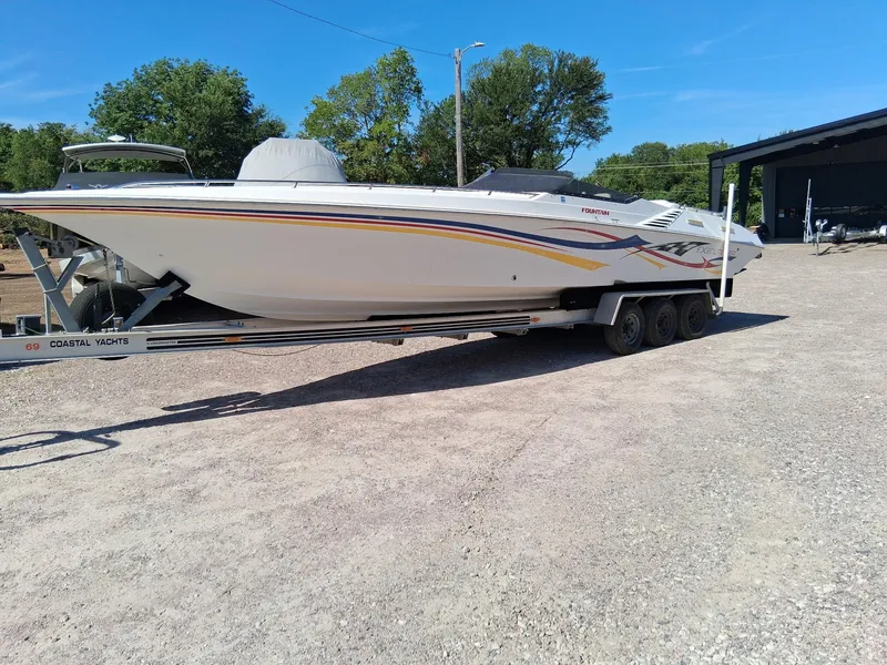 Slide: The Image of 2003 Fountain 35 Executioner boat on trailer, parked outdoors under clear blue sky. - 20
