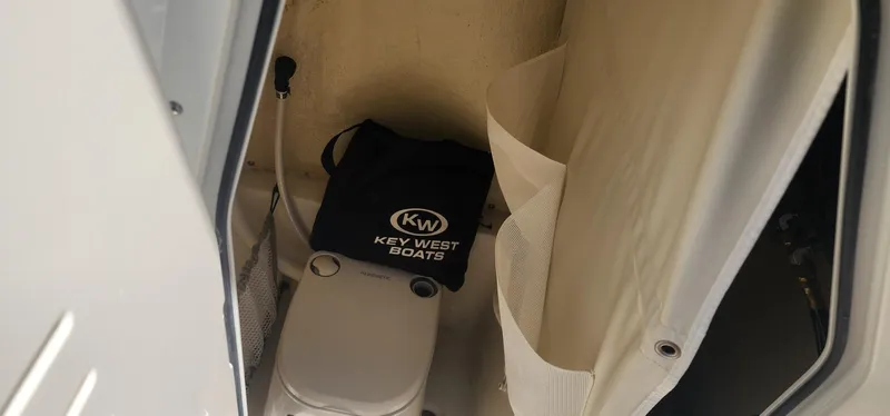 Slide: The Image of 2024 Key West 219fs boat interior with portable toilet and storage bag. - 22